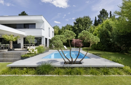 Ein begrünter Garten mit Pool und einem weißen Haus.
