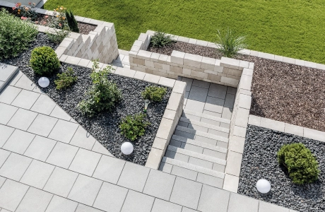 Terrasse mit Treppenabgang aus Betonstein und Terrasiertem Hang abgestützt mit einer Naturstein mauer  und angelegten udn bepflanzten Beeten.<br>