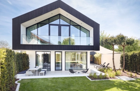 Feine Designfliesen aus Beton in Fischgräten-Optik, für die Gestaltung im Innen- und Außenbereich, sowie für die Wand und dem Boden, in einem modernen zweistöckiges Haus mit großflächigen Glasfenstern mit Terrasse, Whirlpool und Liegefläche