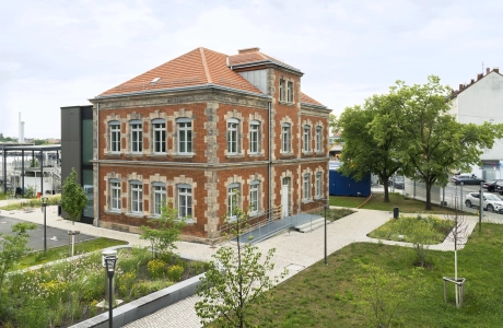 Renoviertes Hauptgebäude der rekoSUN Stadtentwässerung in Nürnberg mit Backsteinfassade, begrünten Außenanlagen und Wegen aus GDM.ACENTRO stone.