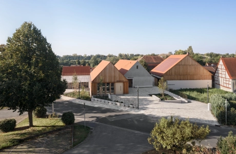 Wohngebiet mit modernen und traditionellen Häusern, baumgesäumten Straßen und klarem Himmel.