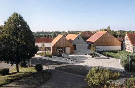 Wohngebiet mit modernen und traditionellen Häusern, baumgesäumten Straßen und klarem Himmel.