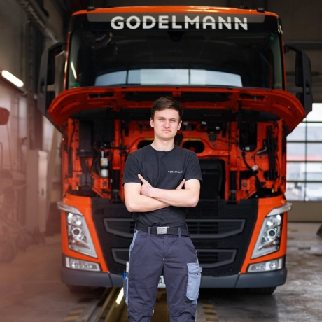 Azubi steht selbstbewusst vor einem GODELMANN Lkw.