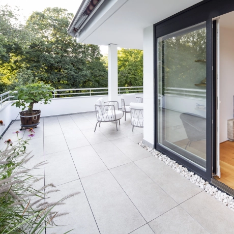 Eine Dachterrasse ist mit großformatigen Fliesen in 2 cm Dicke in Kreuzfuge verlegt. 