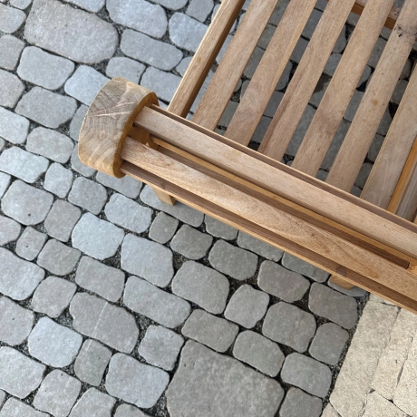 Eine Holzbank auf einem Pflasterbelag, umgeben von einer ruhigen und einladenden Umgebung.
