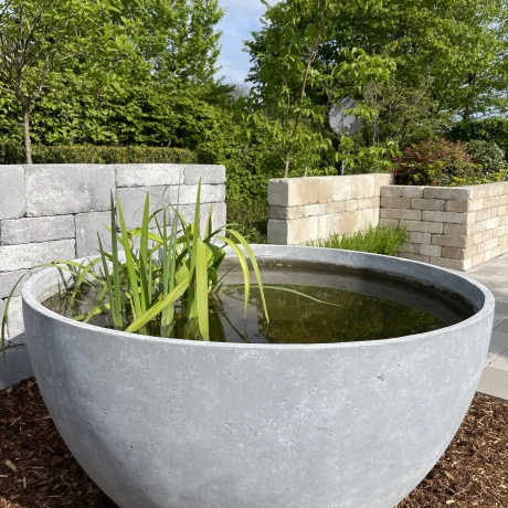 Large stone-colored planter filled with water and plants