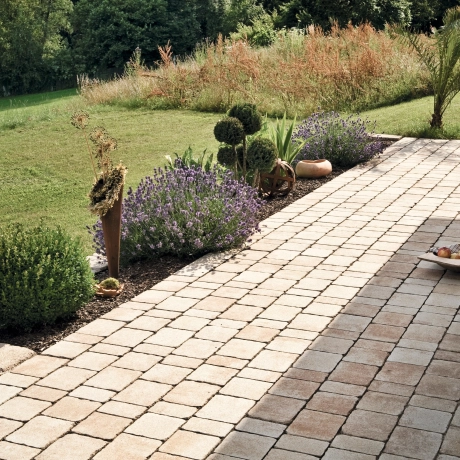 Eine gepflasterterte Terrase mit Bepflanzung und Garten.