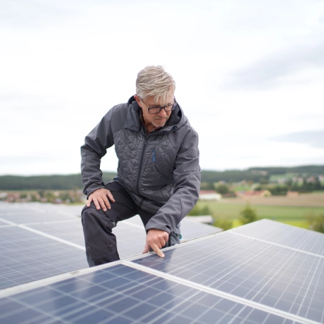 PV systems on the roofs of the production halls. A person is inspecting the surface of the photovoltaic systems.