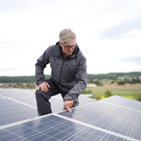 PV-Anlagen auf den Dächern der Produktionshallen. Person kontrolliert die Oberfläche der Photovoltaik-Anlagen.