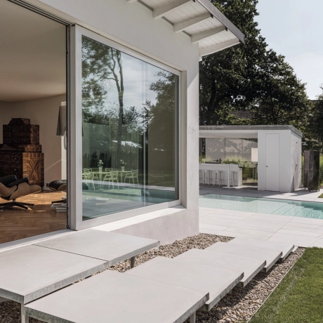 Freischwebende Treppe zum Garten mit Pool und großformatigen Terrassenplatten  in hellgrau und sichtbeton