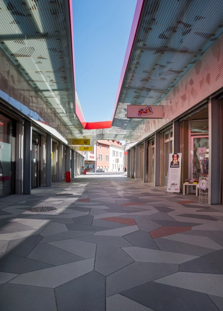 Vorplatz mit Belag aus mehrfarbigen Polygonalplatten vor Eingang zu Einkaufszentrum
