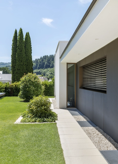 Private modern garden with sandstone-colored terrace and lots of greenery