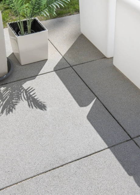 Nahaufnahme von grauen GDM.NUEVA light Platten. Darauf stehen Pflanzgefäße mit grünen Pflanzen. 