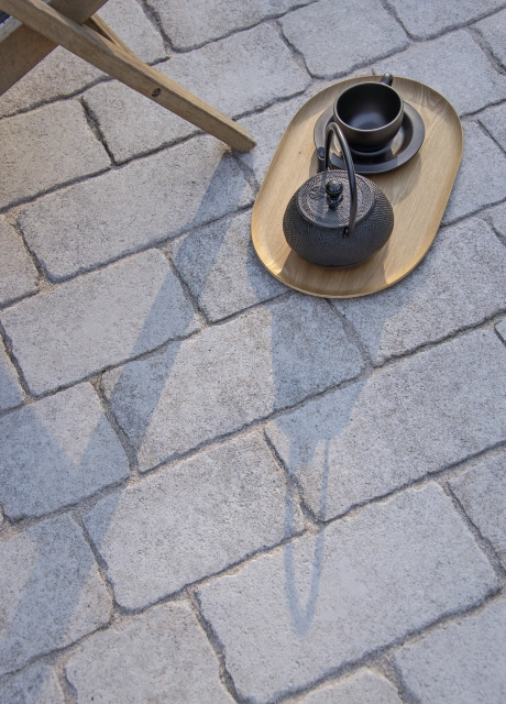 Nahaufnahme der hellen Fläche aus GDM.CAMPA stone, mit einem Tablett, einer Teekanne und einer Tasse als dekoratives Element.