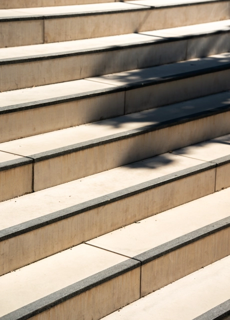 Nahaufnahme einer kalksteinfarbenen Treppe aus GDM.MASSIMO step mit schwarzem Kontraststreifen an der Trittkante.