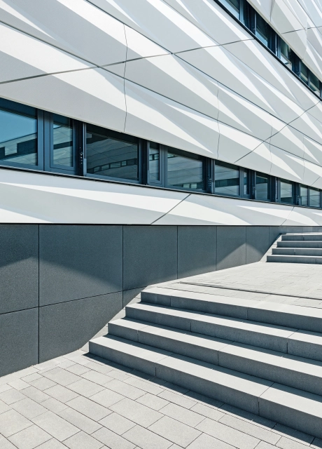 Gray staircase in front of large office building with modern, white concrete façade