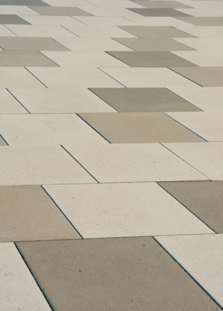 Nahaufnahme einer gepflasterten Fläche mit hellem und dunklem kalksteinfarbenem GDM.SCENIC stone, bei der die unterschiedliche Farbgebung der Betonsteine deutlich sichtbar ist.