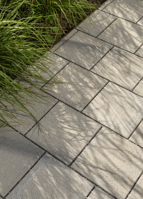 Nahaufnahme einer gepflasterten Fläche mit dem grauen GDM.SCENIC individual. Daneben sind grüne Gräser.