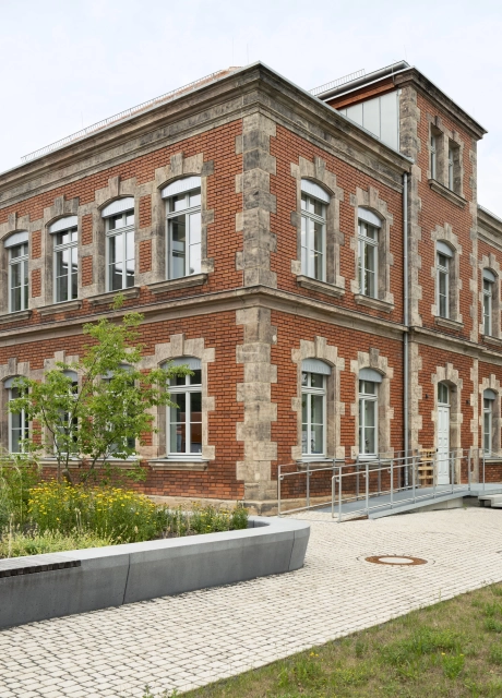 Historisches Gebäude der RekoSUN Stadtentwässerung Nürnberg mit Wegen GDM.ACENTRO stone in Granit Perlmut-Gelb im Vordergrund.