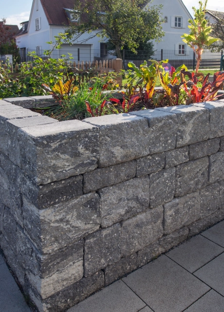 Grau-Schwarzes Hochbeet aus GDM.DECA wall auf gepflastertem Untergrund. Im Beet wächst grün-roter Salat. 