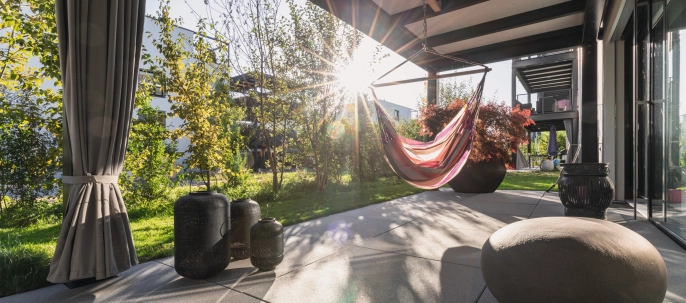 Sonnige Terrasse mit großformatigen Platten und Hängeschaukel.