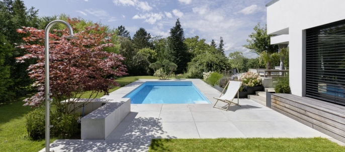 Begrünter Garten mit Pool und großformatigen Terrassenplatten auf einem Privatgrundstück.