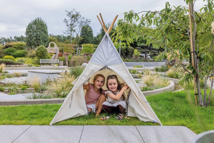 Zwei Mädchen schauen lächelnd aus einem weißen Tipi.
