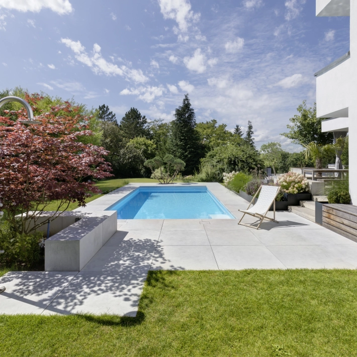 Landscaped garden with pool and large-format patio slabs on a private property.