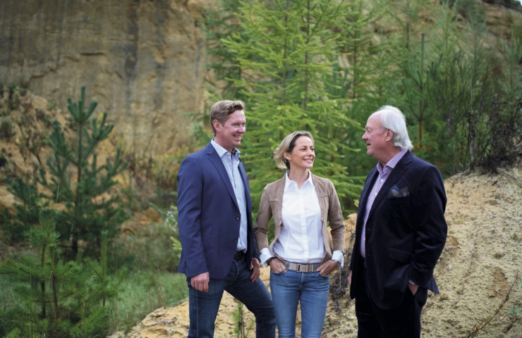 Die Geschäftsleitung von GODELMANN, Bernhard Silvia und Bernhard senior, stehen vor einen bewachsenen Sandstein-Wand.