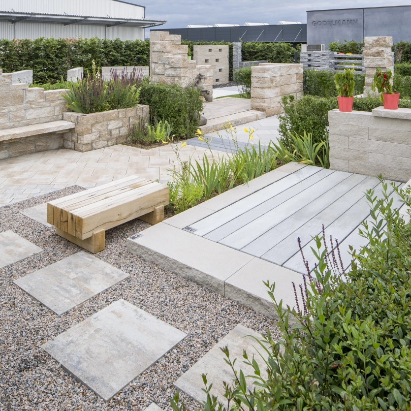 Rustikaler Garten mit Terrassenplatten, Mauern, Stufen und Sitzbänken.