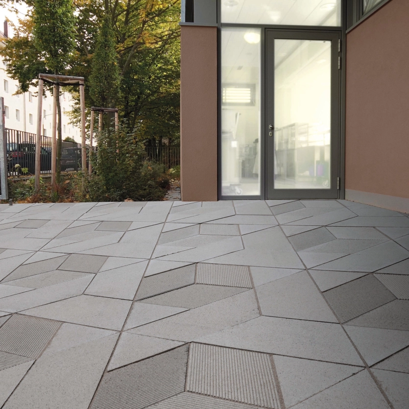 GDM.DEDALE stone in einer Hofeinfahrt mit Blick in den grünen Garten.