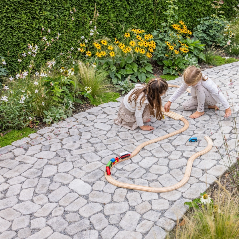 gepflasterter Weg mit grüner Bepflanzung und zwei Kindern