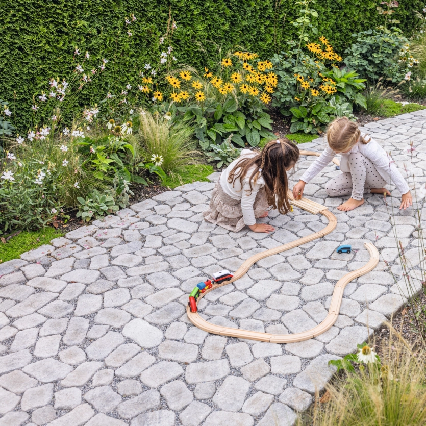 gepflasterter Weg mit grüner Bepflanzung und zwei Kindern
