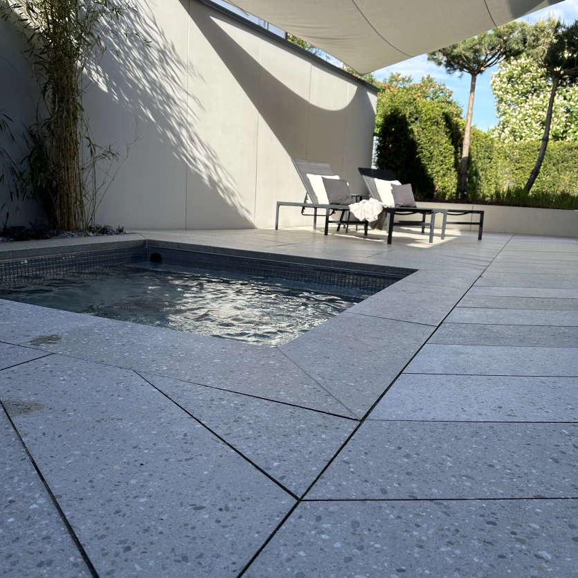 kleiner in den Boden eingelassener Whirlpool. Terrasse belegt mit GDM.AWA tile