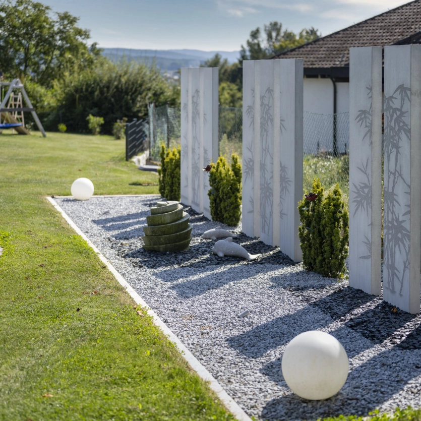 Dekorativer Sichtschutz aus mehreren Beton Stelen mit floralem Motiv in einem modernen Garten.