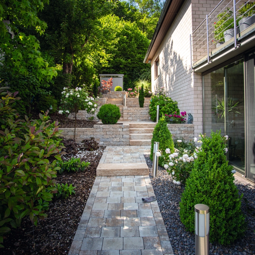 grün bewachsener Garten mit Weg und Stufen aus Beton
