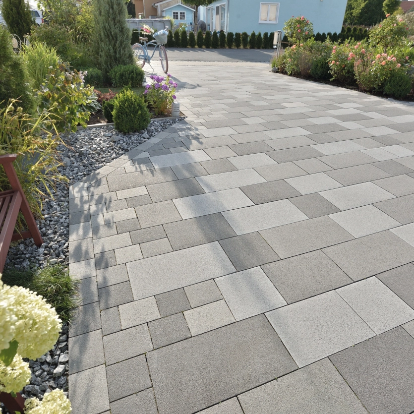 Private driveway with granite-colored paving surrounded by plants.