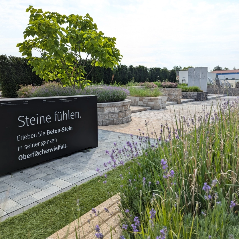 Grüner Garten mit Pflastersteinen und Hochbeeten.