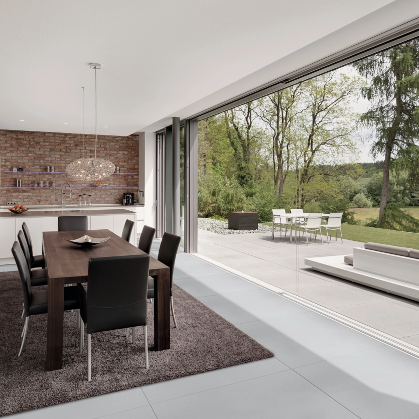 Großzügiges Wohnzimmer mit großer Panoramaschiebetür als nathlosen Übergang zwischen Terrasse und Essbereich