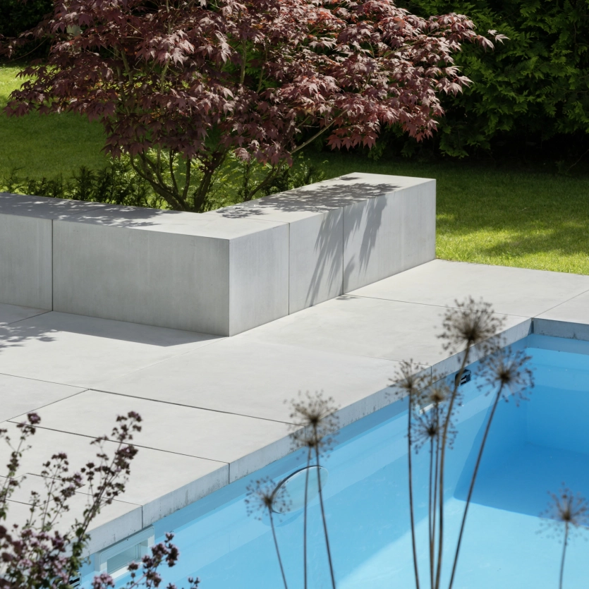 Ein begrünter Garten mit Beton Sitzblock und Pooleinfassung
