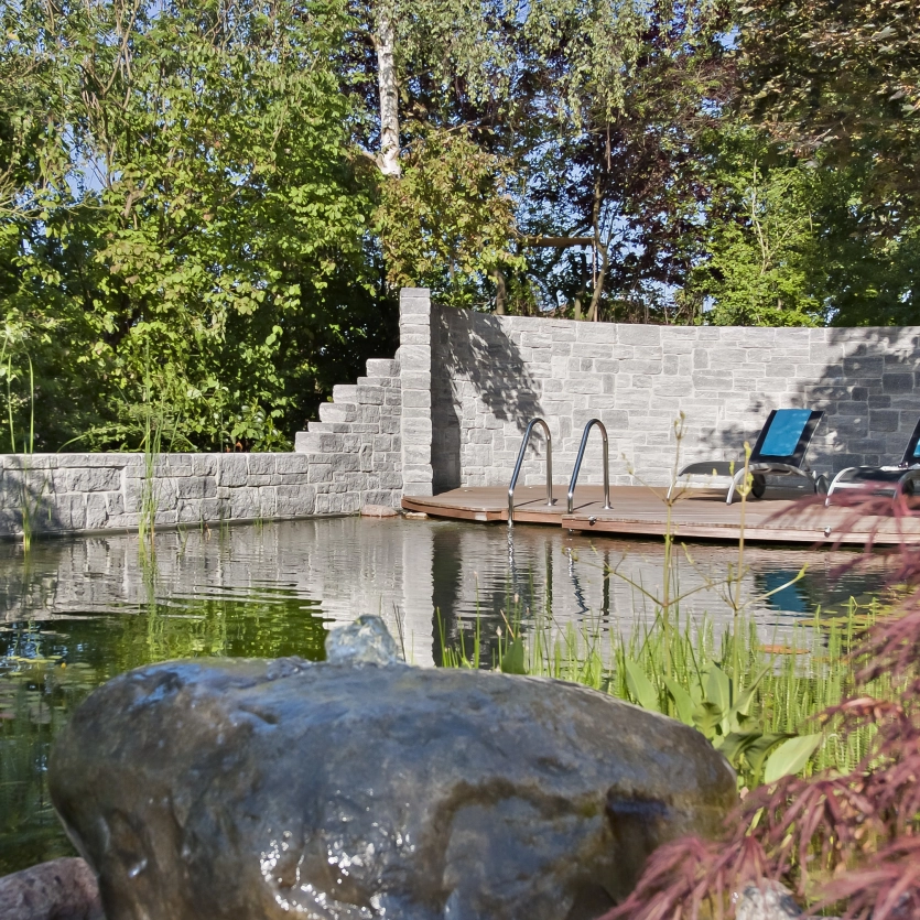 Natürliche Mauer aus Beton als Wechselmauerwerk mit einem Naturpool