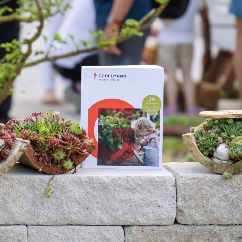 Gartenbuch auf einer Gartenmauer mit Pflanzen