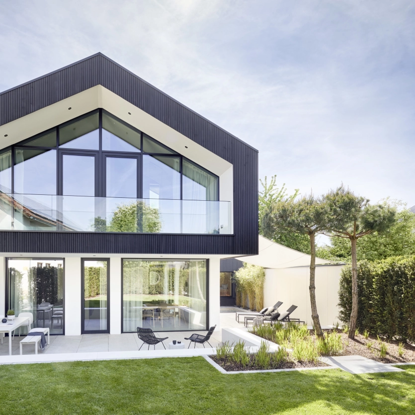 Modernes Haus mit Glasfassade und Terrassenplatten aus Beton.