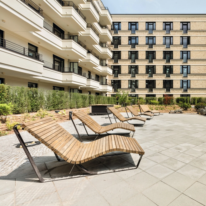 SpreeOneLiving in der Dovestraße in Berlin mit begrünter Dachterrasse und Liegen aus Holz.