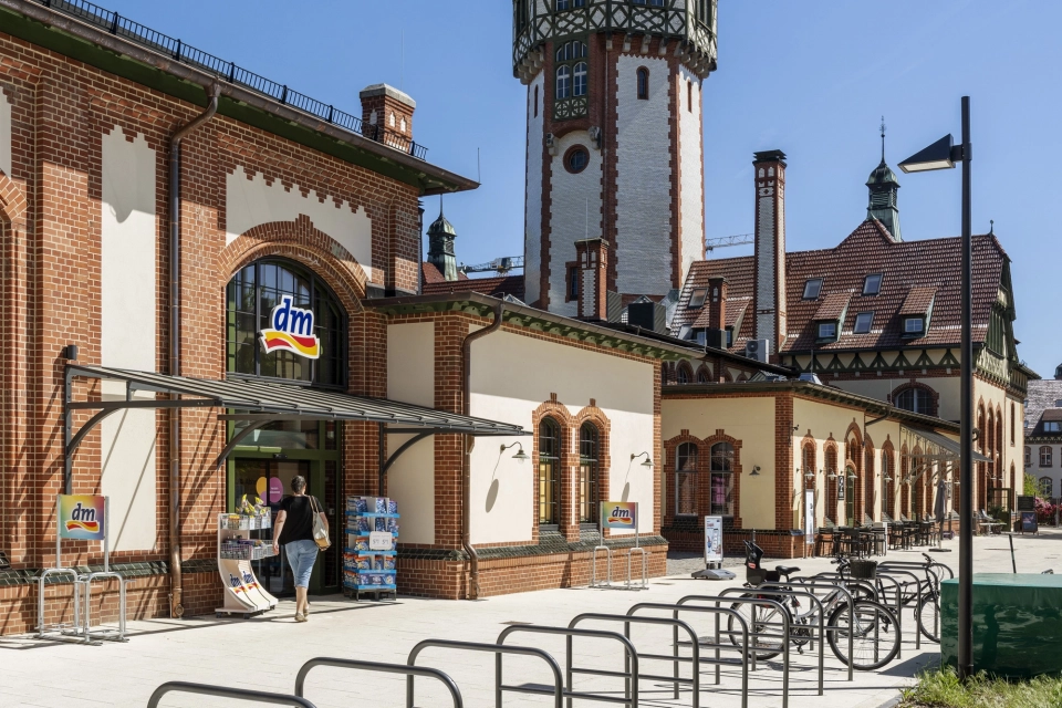 Moderner Fahrradparkplatz am Marktplatz Beelitz-Heilstätten mit GDM.NUEVA Stone Pflastersteinen in Sandstein-Uni vor dem historischen Wasserturm.
