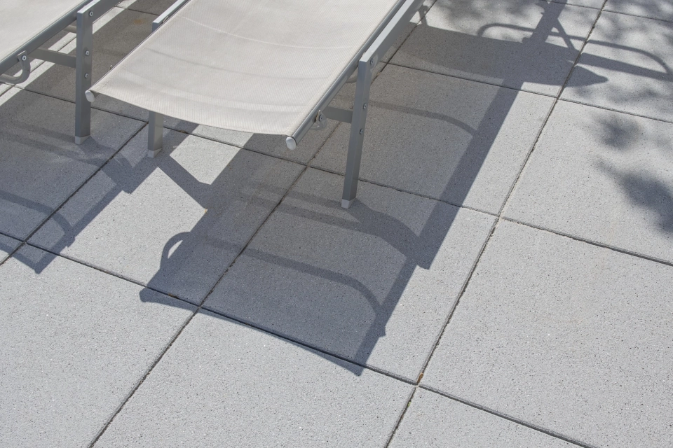 Mehrere graue Gartenliegen mit schwarz-weiß gestreiften Kissen, welche auf GDM.NUEVA light Platten stehen.