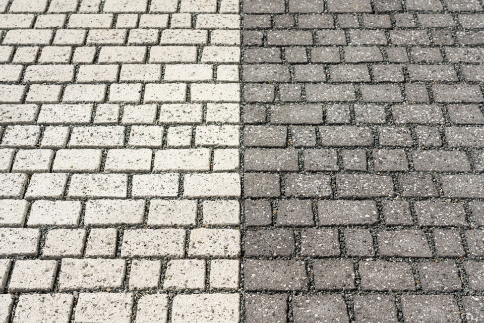 A two-part paved area consisting of anthracite and white-colored, small-format concrete blocks in a row.