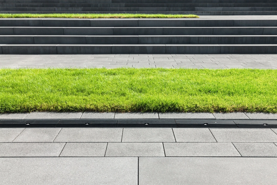 Paved floor with green strips in front of a staircase