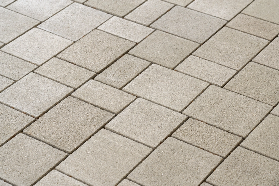 A paved area consisting of climate-positive concrete blocks laid in a wild bond. The ecological surface covering has a stainless steel shot-blasted, beige surface 