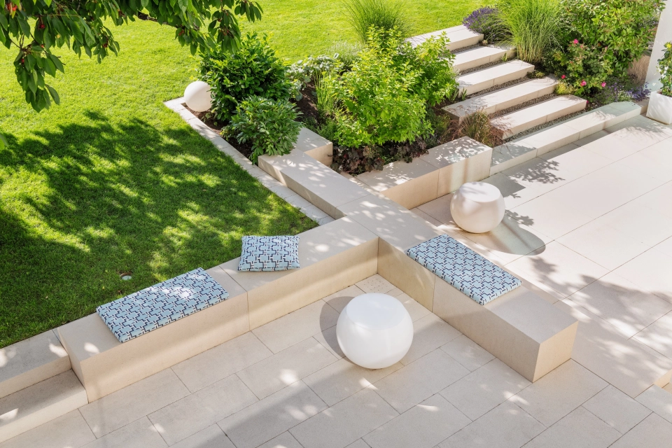 Privater moderner Garten mit sandsteinfarbener Terrasse und viel Grün